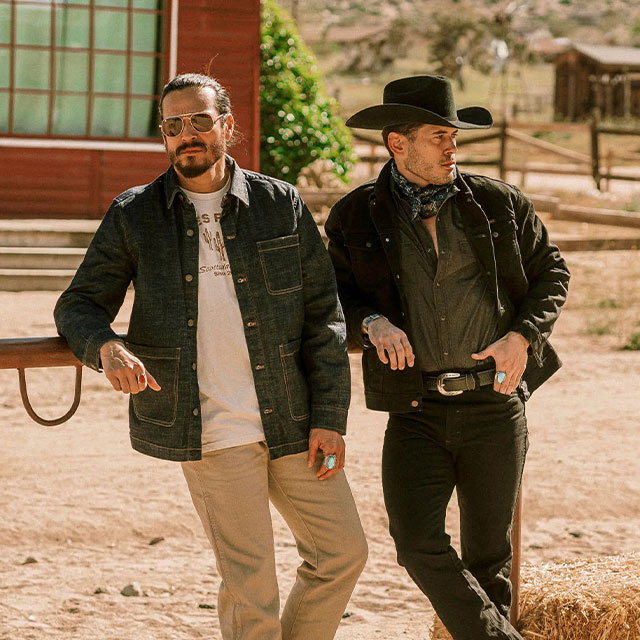 Two cowboys leaning on a fence